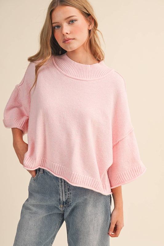 Woman wearing a pink sweater and jeans on a beige background